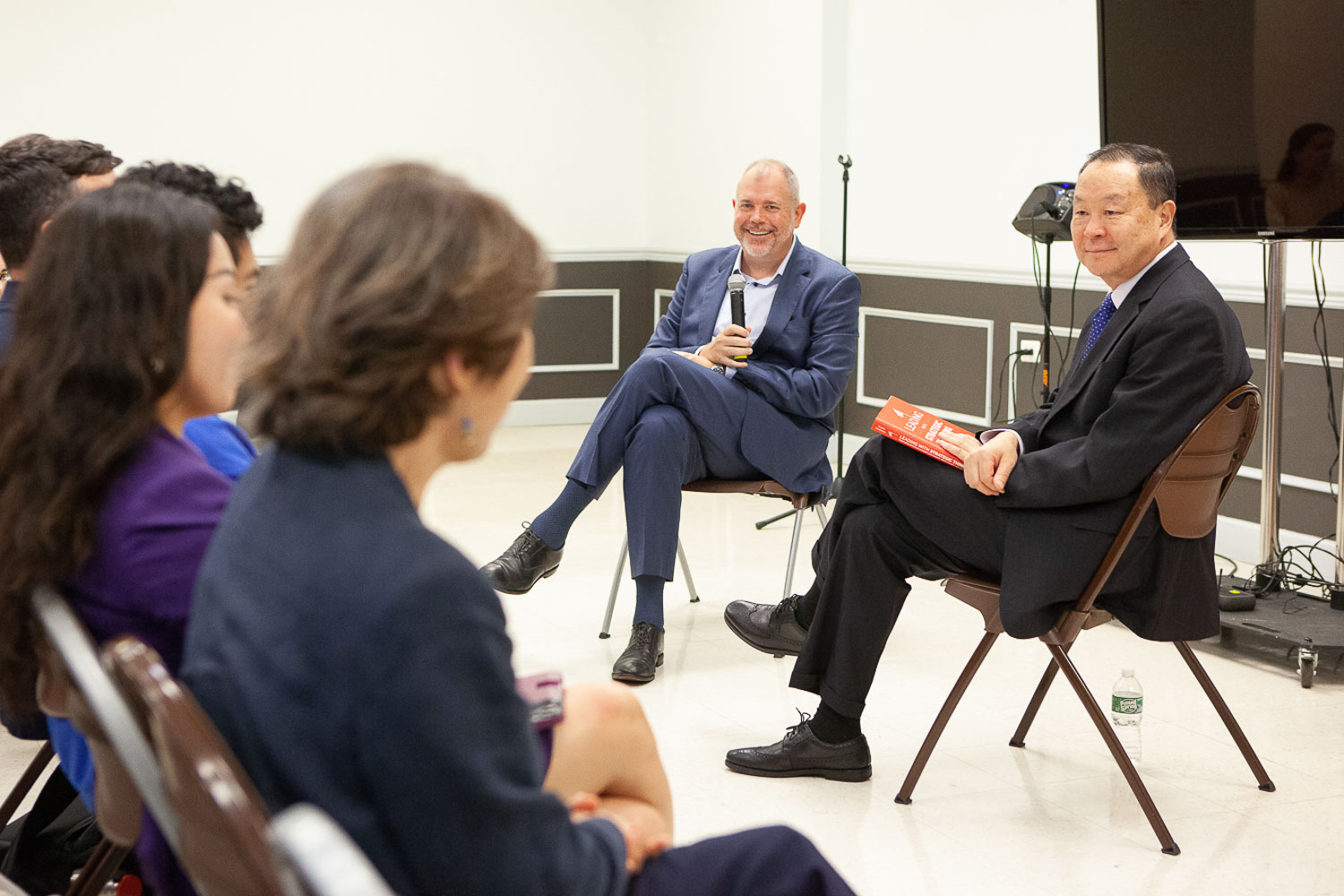 Murray Koppelman School of Business Executive-In-Residence and Aon Executive Vice President Aaron Olson (left) and Dean Qing Hu (right) discuss the insurance industry in front of an audience of students and faculty in spring.