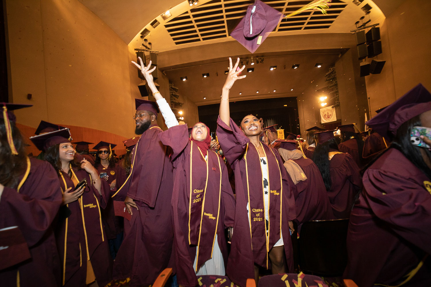 Returning alum toss their caps at the conclusion of the 2022 Comeback Commencement in the Claire Tow Theater in Whitman Hall.